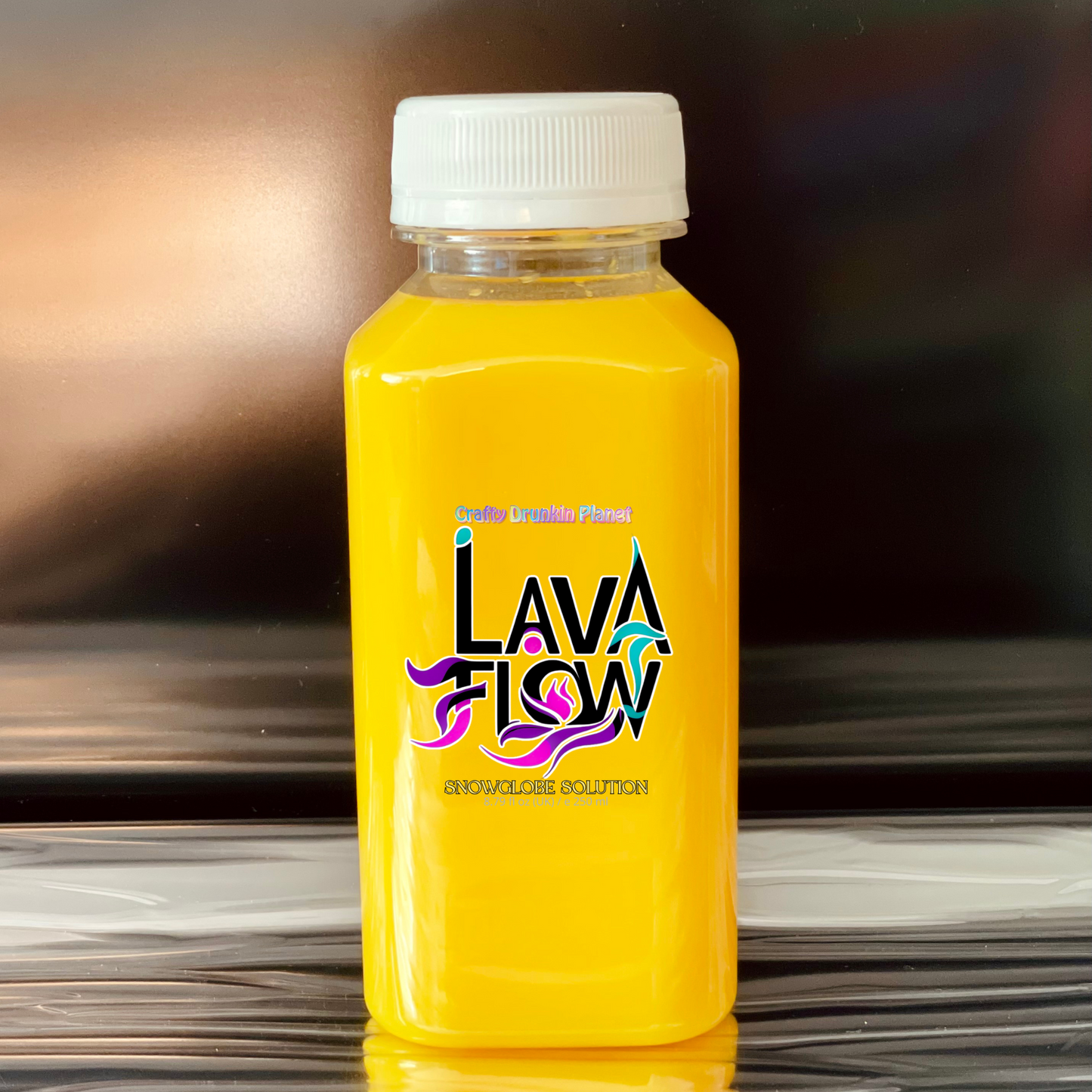 Moon Yellow bottle labeled 'Lava Flow' snowglobe solution on a reflective surface with a blurred background