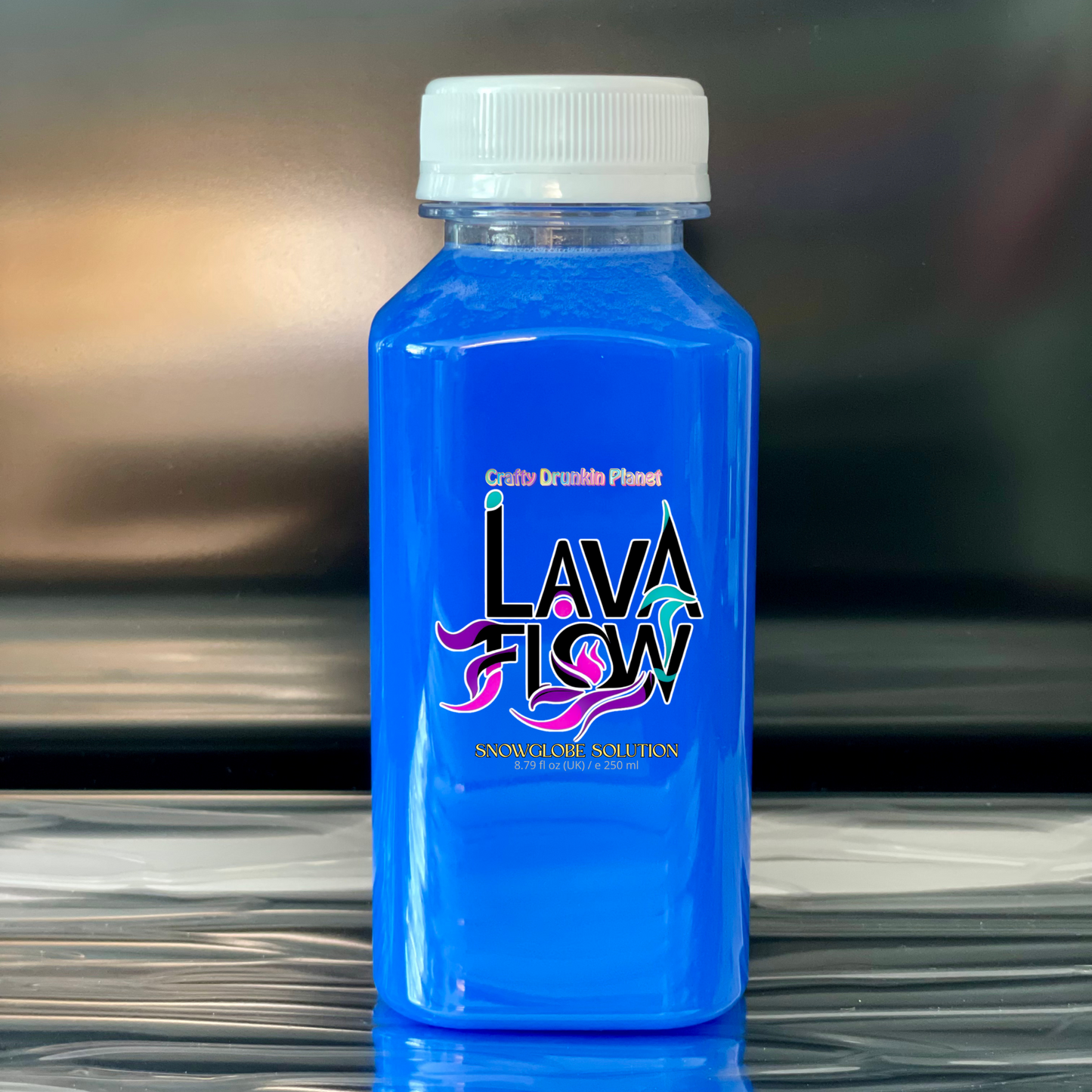 Cobalt Blue bottle of Lava Flow snowglobe solution on a reflective surface with a blurred background