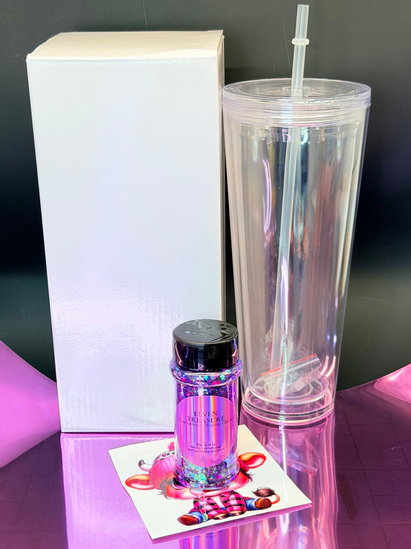 snow globe tumbler single set .Clear 24oz tumbler with straw, small bottle, and box on a reflective surface.